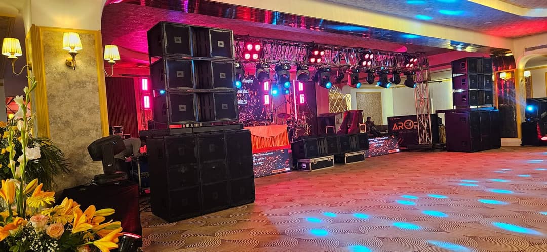 The banquet hall set for a function, with the stage lit and the house sound system stacked beside it